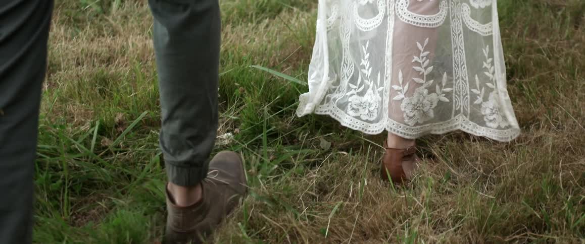 Legs of a man and a woman walking on grass