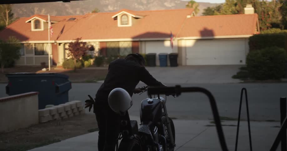 Man rolls motorcycle out of garage then uses the kickstand