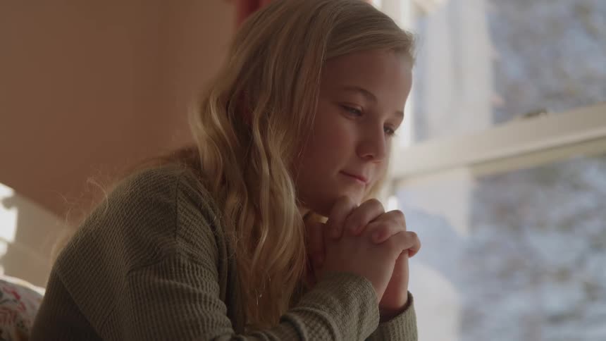 Girl with closed eyes and hands clasped in a prayer position