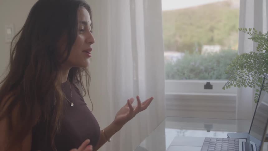 Woman talks cheerfully in a video call in front of the laptop
