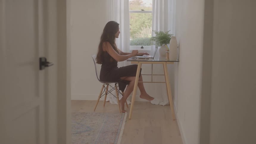 Woman sitting at a desk working on a laptop in a bright room
