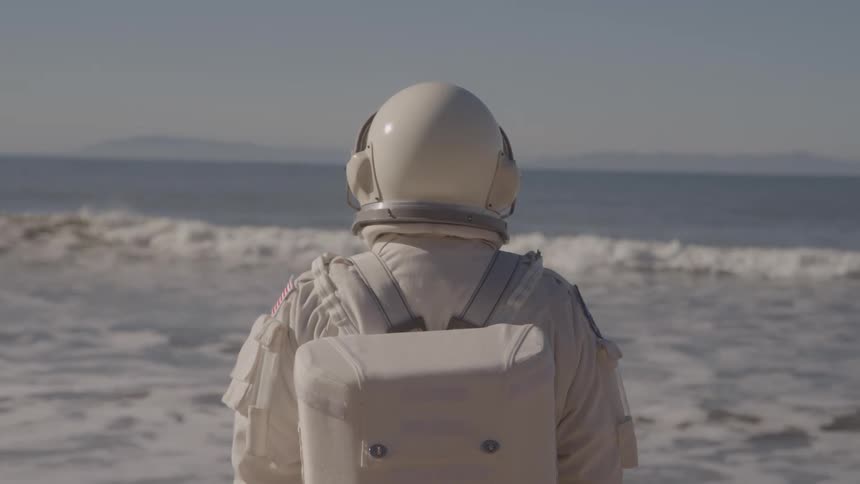 The astronaut is standing on the beach