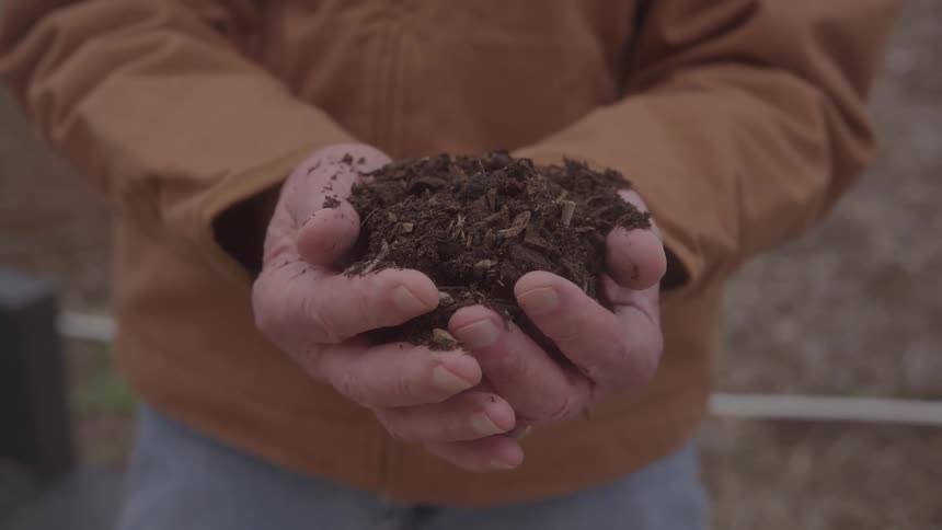 The man holds a pile of dirt in his hands