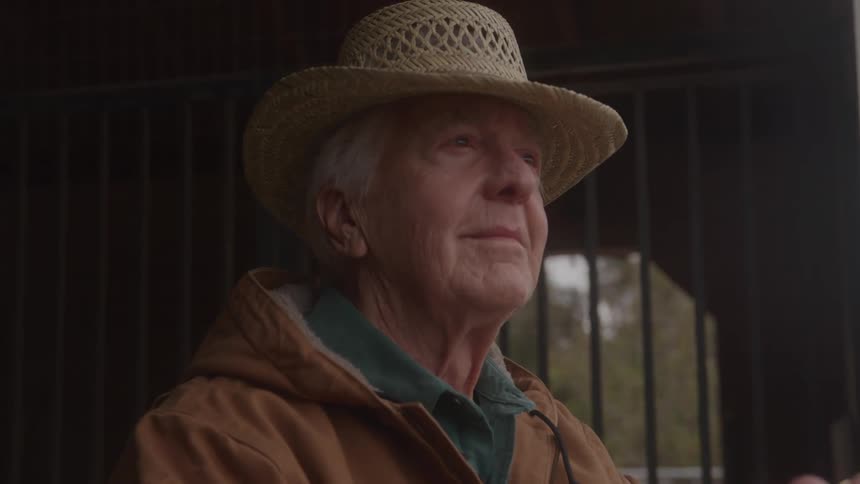 Elderly man wearing a straw hat looking thoughtfully into the distance