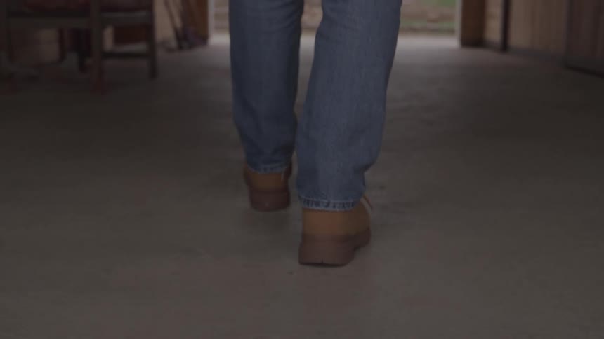 Person walking through a concretefloored corridor wearing boots and jeans