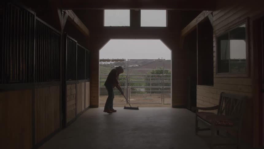 The man is sweeping the dark stable
