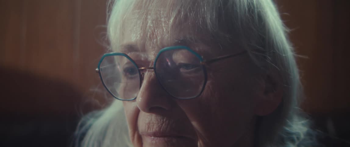 Close up portrait of an elderly woman reading while sitting in a room during daytime