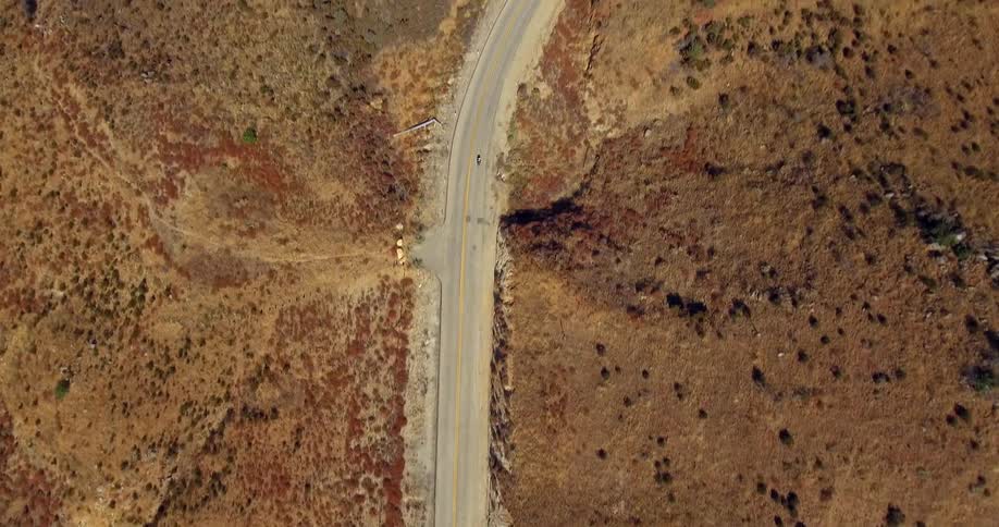 A motorcyclist rides on a remote road
