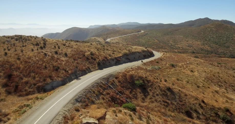 A motorcyclist rides on a winding road in the mountains