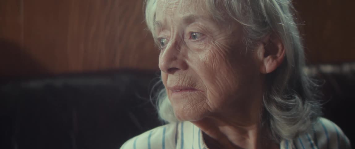 An elderly woman looks to the side with a confused and sad expression