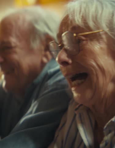 An elderly couple laughing together indoors