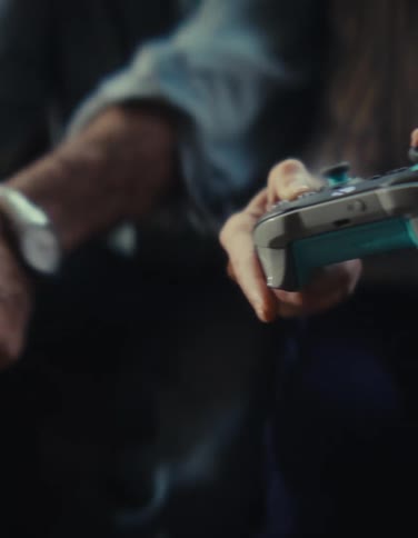Two people playing video games side by side with controllers in hand