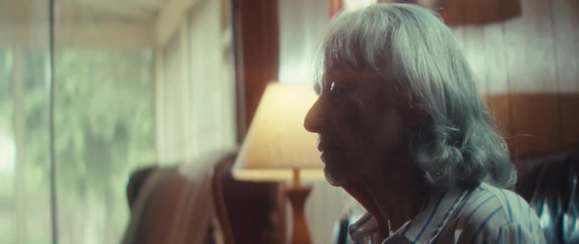 Elderly woman sits alone in her living room during the daytime