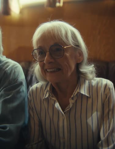 Close up of an elderly man and woman playing video games with controllers while sitting in a living room during daytime