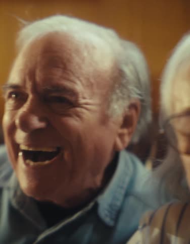 The man and woman sit together laughing and talking