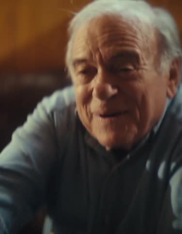 Close up of an elderly man and woman playing video games with controllers while sitting in a living room during daytime