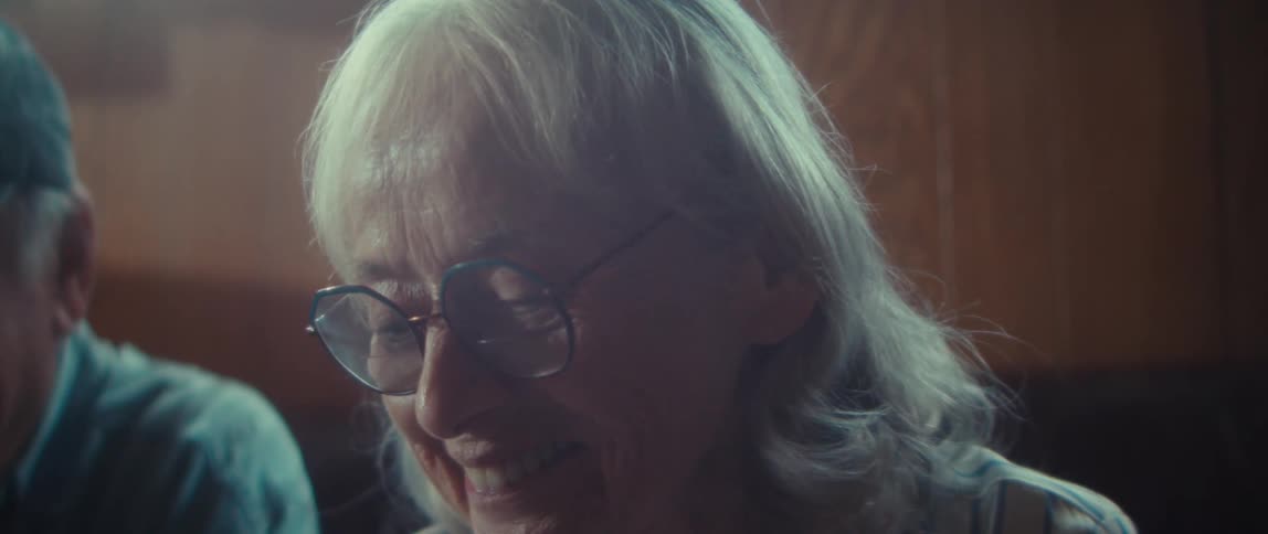 Close up of an elderly man and woman laughing while sitting together on a couch in a room during daytime