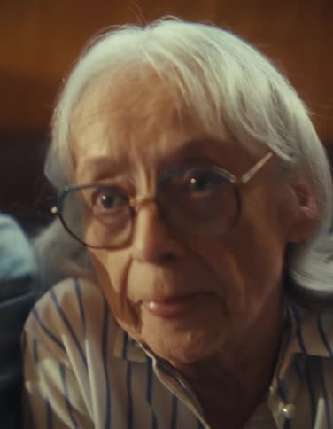 Close up of an elderly man and woman making fun faces while playing video games in a living room during daytime