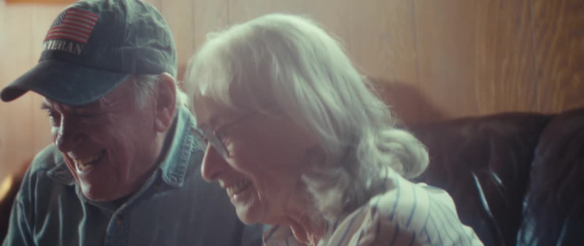 Elderly couple smiling and talking cheerfully indoors