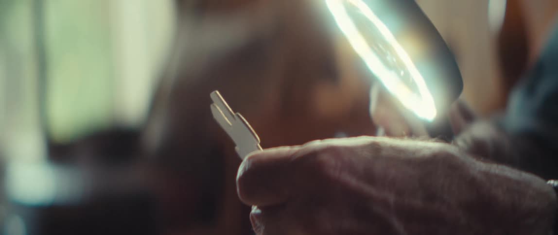 Hand holds a metal key near a circular light in an indoor setting