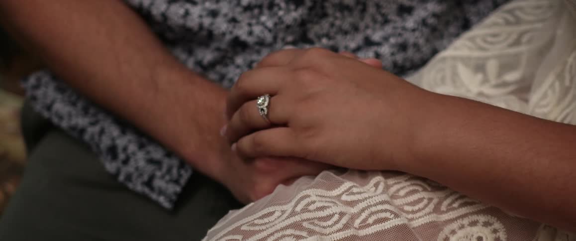 A couple sits holding hands
