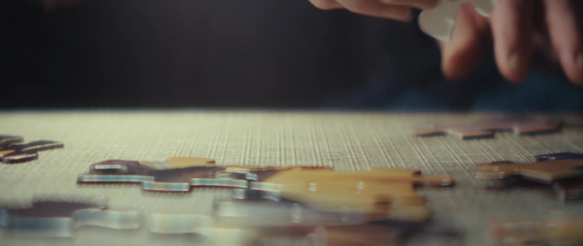 Closeup of a hand picking up puzzle pieces on a table