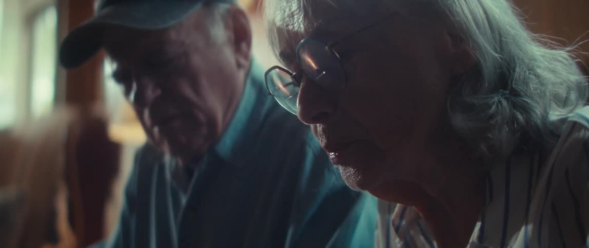 Elderly couple sitting side by side on a couch looking thoughtfully downward