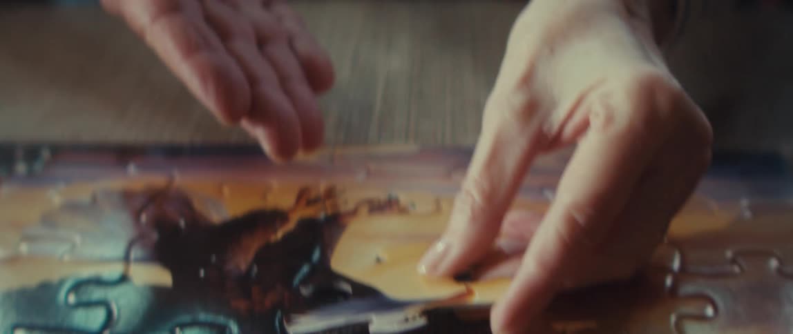 Two people place puzzle pieces together on a table