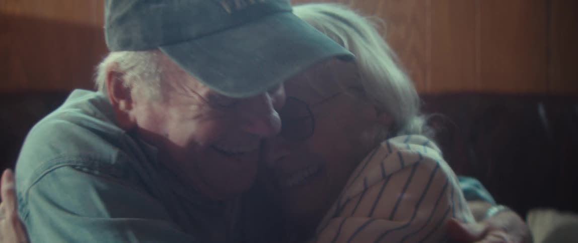 The video begins with a closeup of a puzzle featuring a bird of prey followed by a shot of an elderly couple embracing and smilingthe transition suggests a narrative shift from an activity like puzzling to an intimate joyful moment betwe