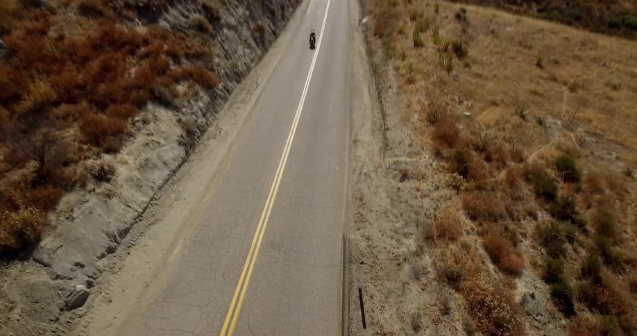 A motorcycle travels on the road on a sunny day