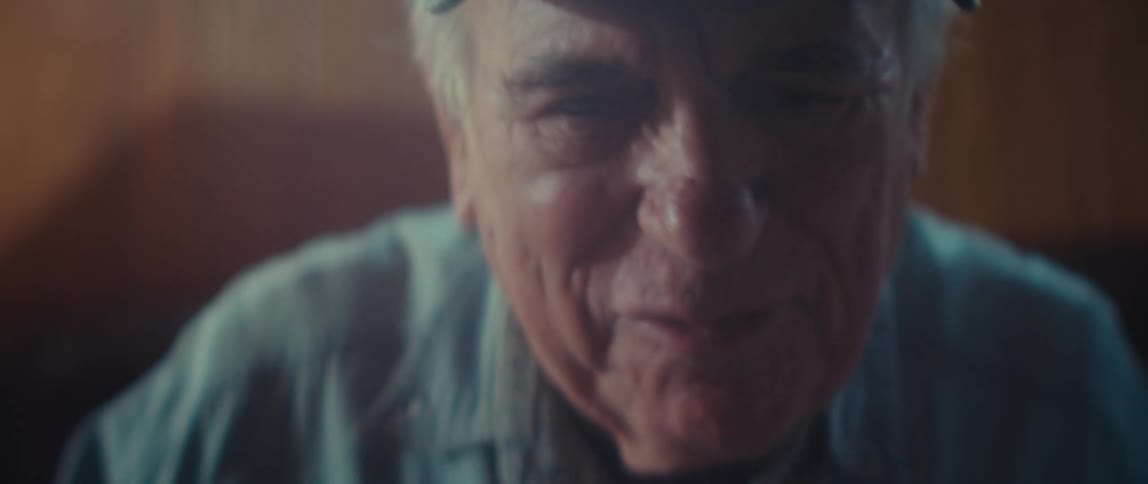The video is a closeup shot of the back of a baseball cap worn by an older manthe hat is denim blue and features an embroidered american flag with the word veteran written beneath it