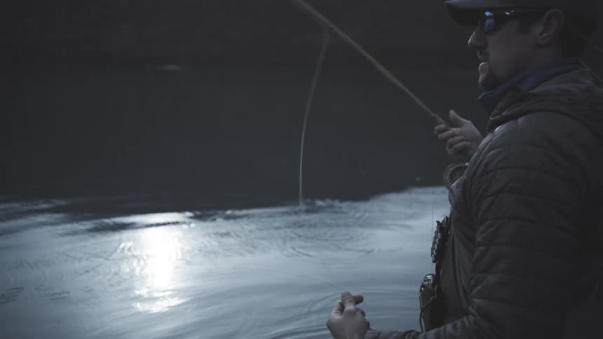 The man fly fishing is standing in the shallow water