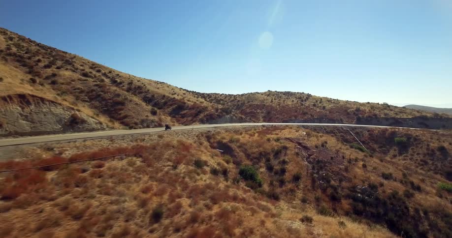 Two people travel by motorcycle on a mountainous country road
