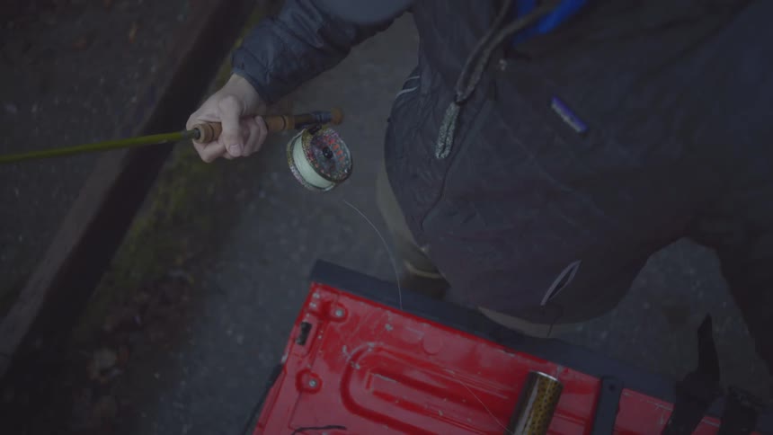 Person preparing a fishing rod with a reel