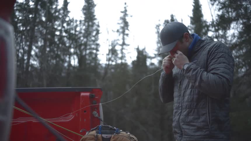 The man tears a fishing line in the bake of his truck
