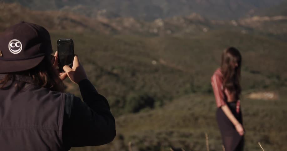 Man takes photos of girl posing before a beautiful valley