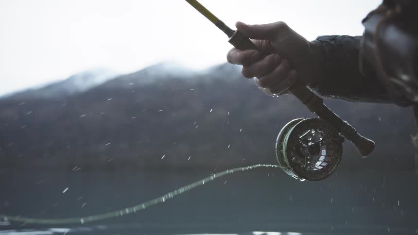 The man pulls out the fishing line from his rod