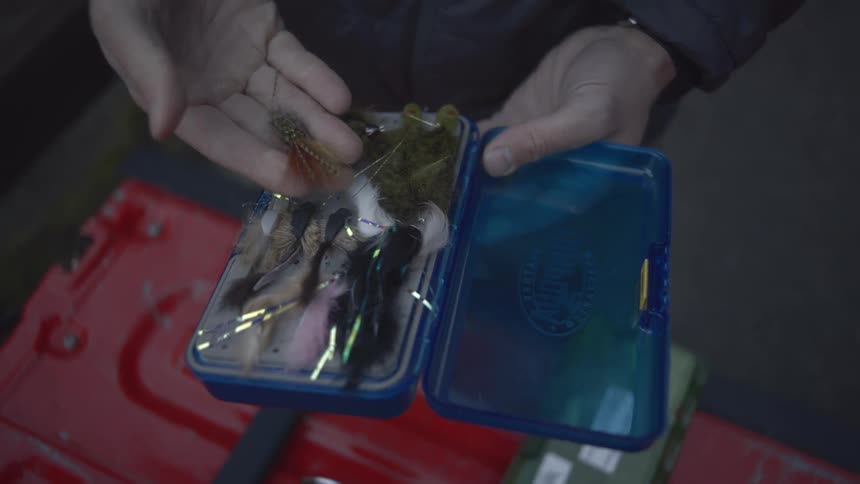 Person holding a blue box with fishing lures organized in compartments