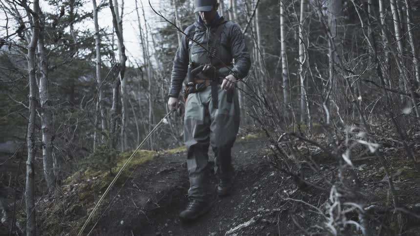 Man walking along a narrow forest trail in cold weather