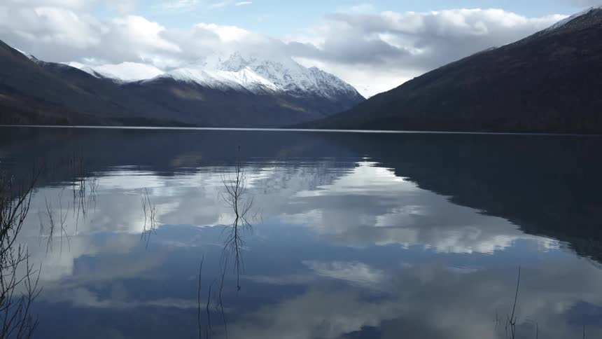 Snow capped mountains mirrored in a calm dark lake