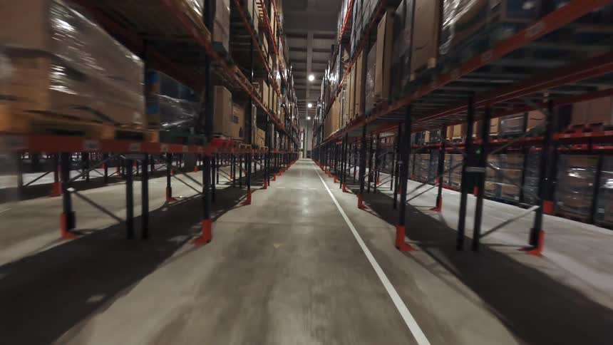 Long warehouse aisle with tall shelves stacked with boxes