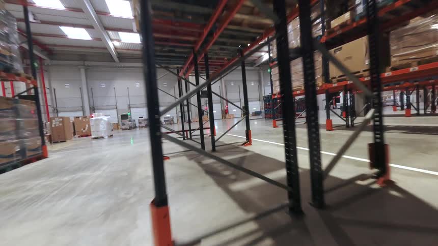 Wide warehouse aisle with metal racks loaded with stacked boxes