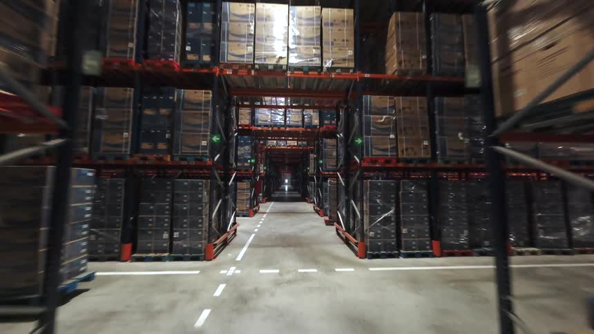 Forklift transporting boxes in an industrial warehouse aisle