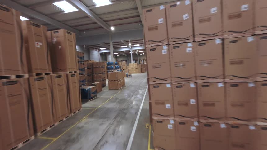A bright warehouse filled with stacked boxes and a forklift