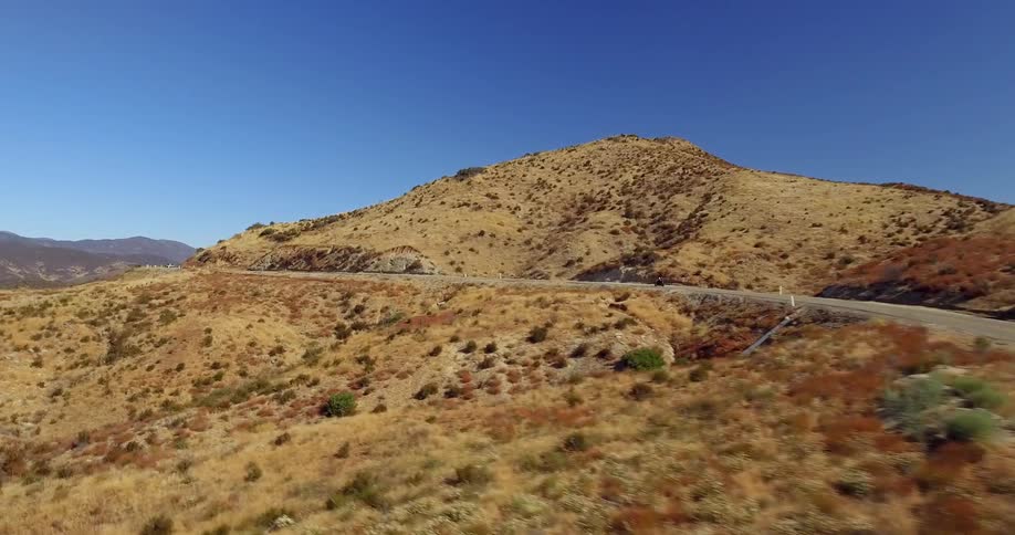 A motorcyclist rides up a hill on a sunny day
