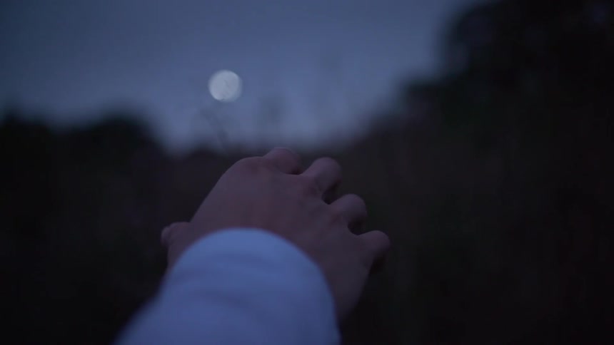 Persons hand pointing towards a moon in the sky