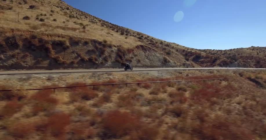 A motorcyclist rides on a rural road on a sunny day