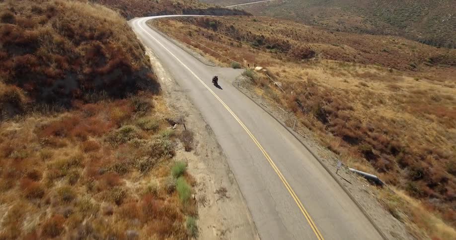 A motorcycle drives down a desert road