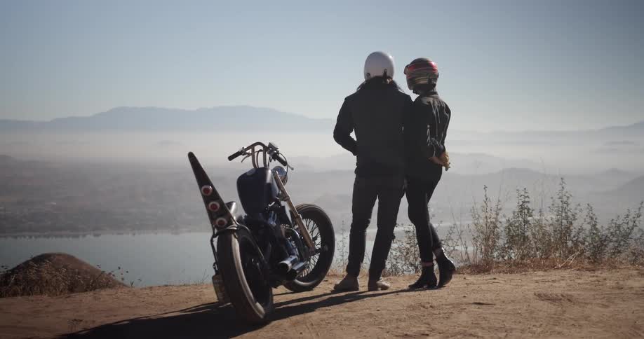Man and woman enjoy a scenic view by their motorcycle