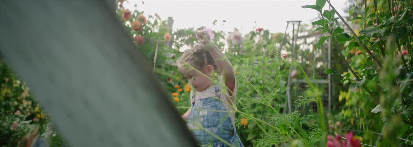A young girl plucking flowers in a colorful garden
